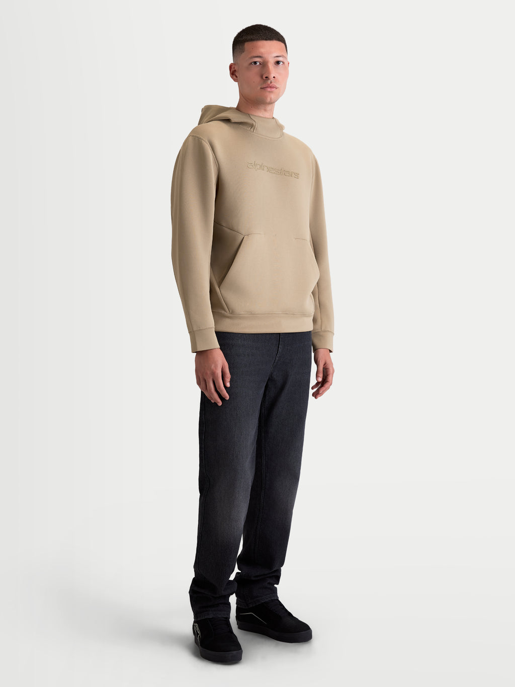 Alpinestars Datrix Hoodie, Herren-Sportswear-Pullover in Putty-Braun, mit tonalem HD-Branding, einer Mesh-gefütterten Kapuze und einer Fronttasche mit Abnäherdetail, am Modell präsentiert für einen lässigen Motorsport-Look.