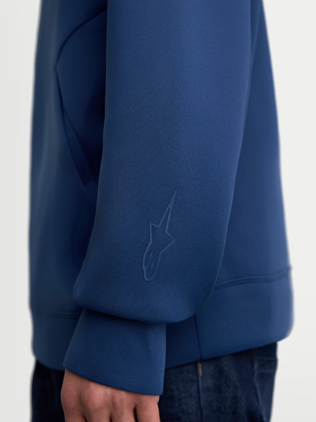 Alpinestars Datrix Hoodie, Premium-Sportswear-Kapuzenpullover, Blau, Nahaufnahme des Ärmels mit tonalem HD-Alpinestars-Logo, gefertigt aus Tri-Blend-Double-Face-Fleece-Gewebe für den Alltag.