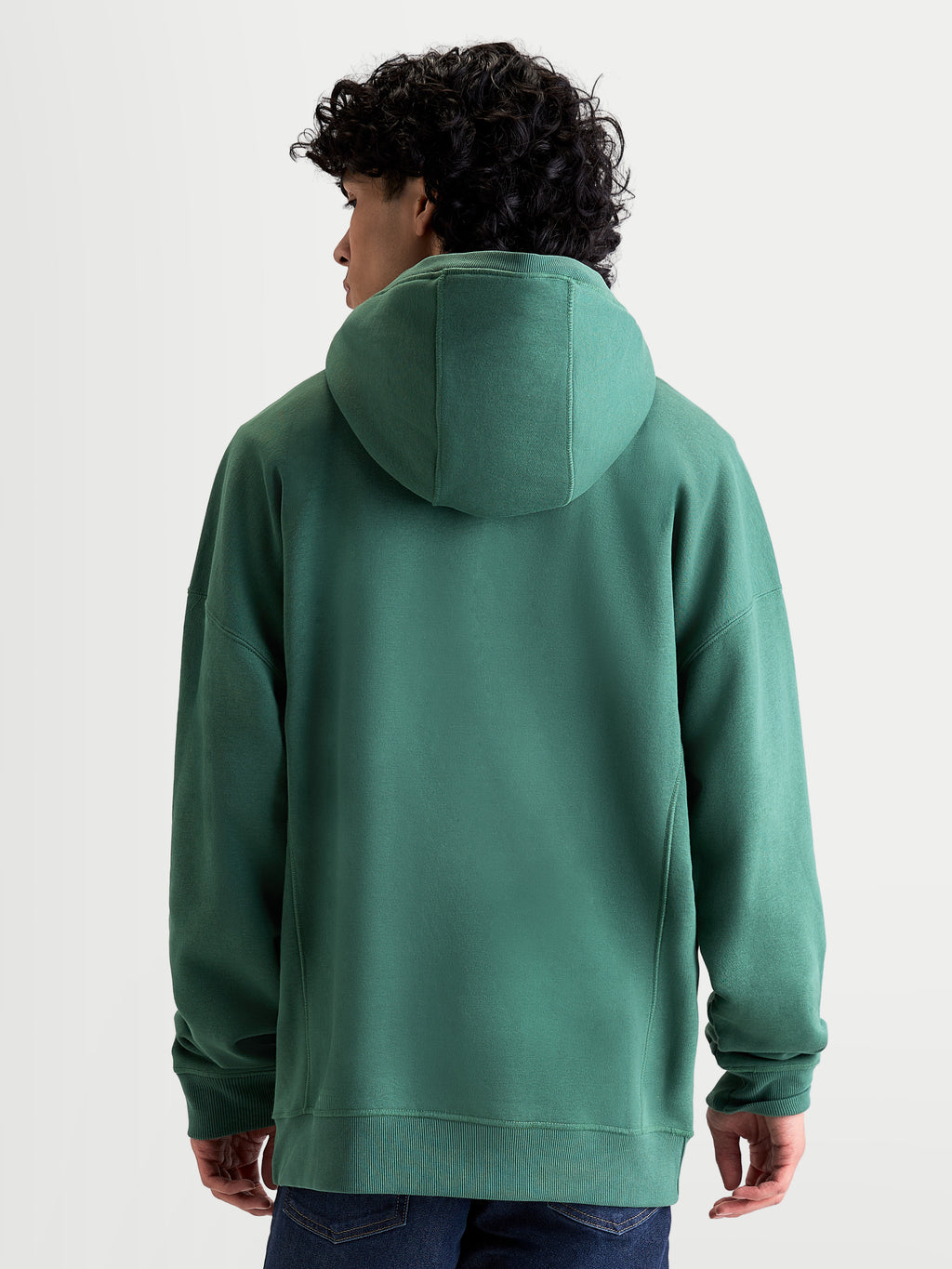 Alpinestars Shaw Oversized Hoodie, grüner Sportswear-Pullover, Unisex Relaxed Fit, Rückansicht am Modell, selbstgefütterte Kapuze und Rippbündchen, weiche Konstruktion aus Baumwolle und recyceltem Polyester-Fleece.