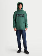 Alpinestars Shaw Oversized Hoodie, Sportswear-Freizeitpullover für Herren, Grün mit schwarzem strukturiertem Alpinestars-Wortlogo, Frontansicht am Model, weiche Fleece-Baumwoll-Mischung mit Kängurutasche und Rippbündchen.
