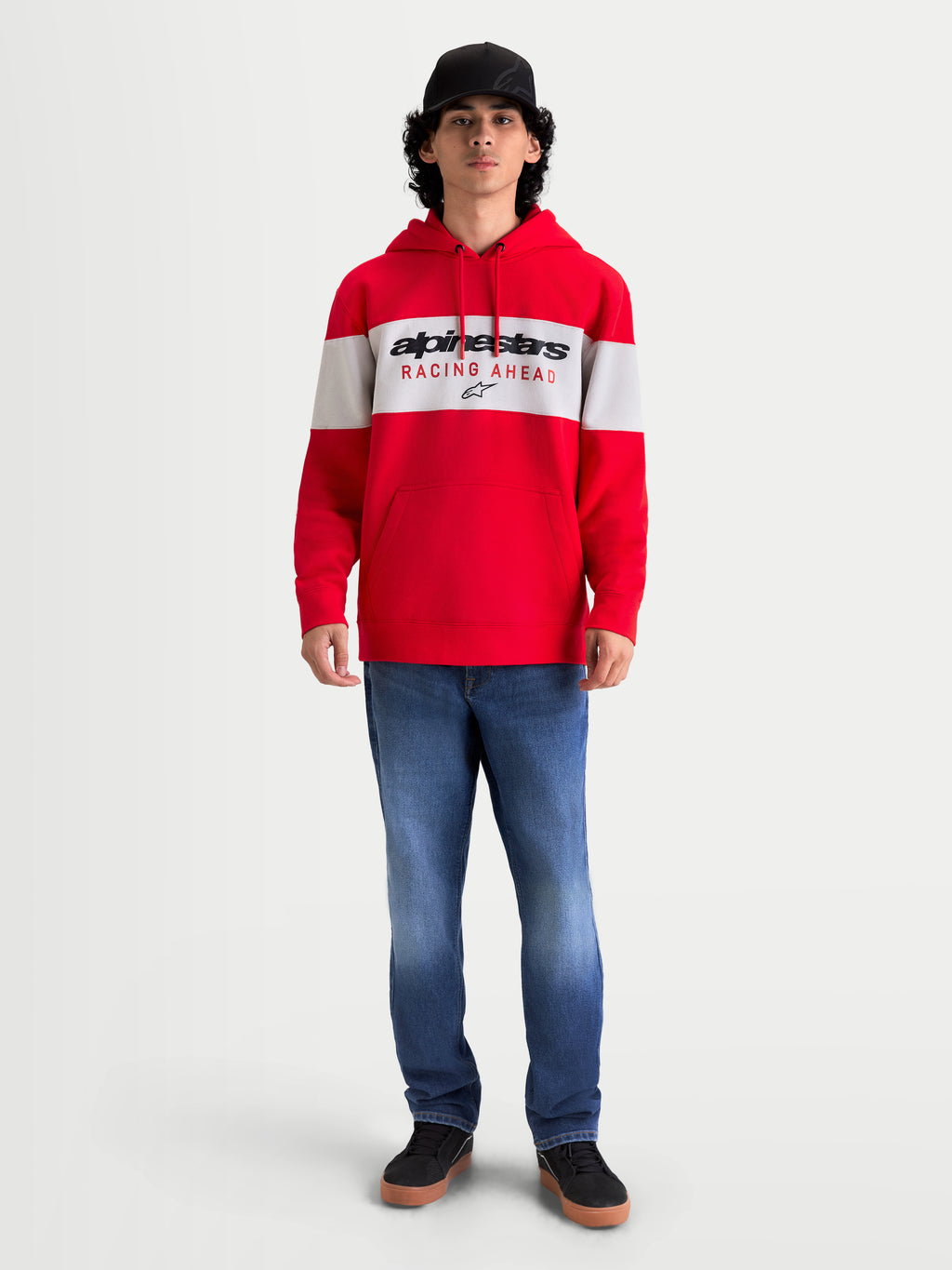 Alpinestars Cubic Hoodie, Sportswear-Kapuzenpullover in Rot und Weiß, mit Color-Block-Design und Alpinestars Racing Ahead Logo auf der Brust. Die On-Model-Ansicht zeigt eine lässige, vom Motorsport inspirierte Passform mit Kapuze, Kordelzug und Rippbündchen, ideal für den Freizeit-Look.
