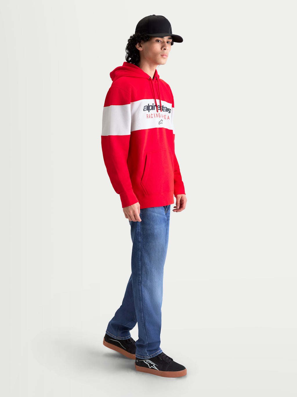 Alpinestars Cubic Hoodie, Herren-Sportswear-Kapuzenpullover in Rot und Weiß mit Color-Block-Design und Alpinestars-Wortlogo auf der Brust. Die Seitenansicht am Model zeigt die Kapuze mit Kordelzug, die Kängurutasche vorne und Rippbündchen für bequemen Off-Bike-Komfort.
