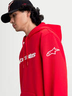 Alpinestars Race Wordmark Hoodie, roter Sportswear-Kapuzenpullover aus Fleece, Ansicht am Modell mit weißem Alpinestars Ageless-Logo am Ärmel und Race Linear Branding auf der Vorderseite, lässiges Motorsport-Design.