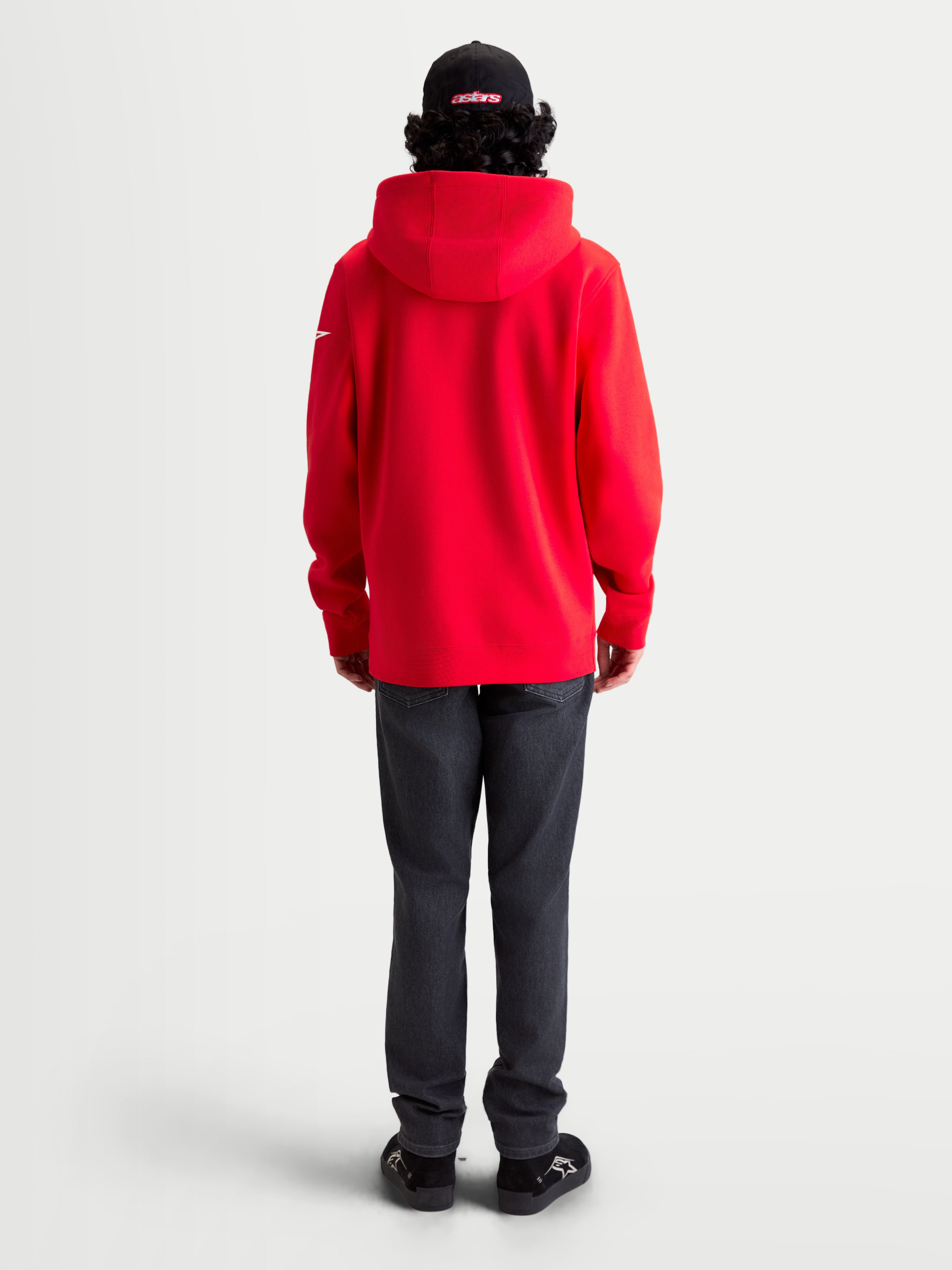 Alpinestars Race Wordmark Hoodie, roter Sportswear-Kapuzenpullover aus Fleece mit weißen Akzenten, Rückansicht am Model mit Kapuze und Ageless-Logo am Ärmel, lässige Motorsport-Bekleidung.