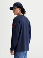 Alpinestars Velocifier CSF Langarm-T-Shirt, Sportswear-Oberteil, Blau und Rot, mit rotem Astars-Logo auf der Schulter und Rippbündchen, Rückansicht am Model, Konstruktion aus 80 % Baumwolle und 20 % recyceltem Polyester.
