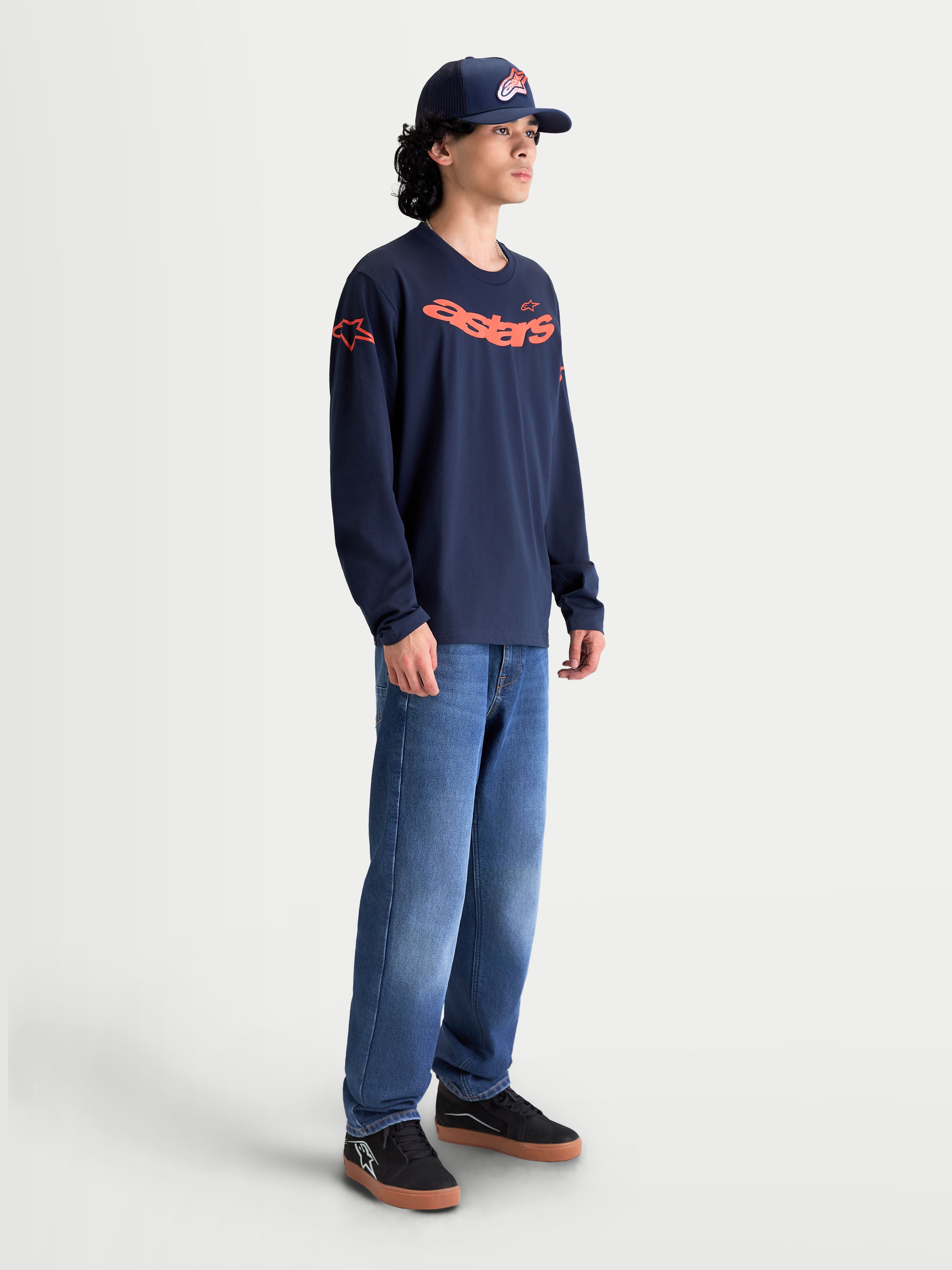 Alpinestars Velocifier CSF Langarm-T-Shirt, Herren-Sportbekleidung, Navy-Blau und Orange, Baumwoll- und Polyester-Mischgewebe mit gebogener Astars-Grafik und Schulterlogos, am Modell für einen lässigen Lifestyle-Look.