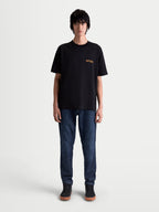 Alpinestars Latitude Oversized CSF T-Shirt, Kurzarm-Sportswear-T-Shirt, Schwarz und Orange, lässige Oversized-Passform, hochwertige Baumwoll-Polyester-Mischung, mit ASTARS Brustgrafik am Model präsentiert.