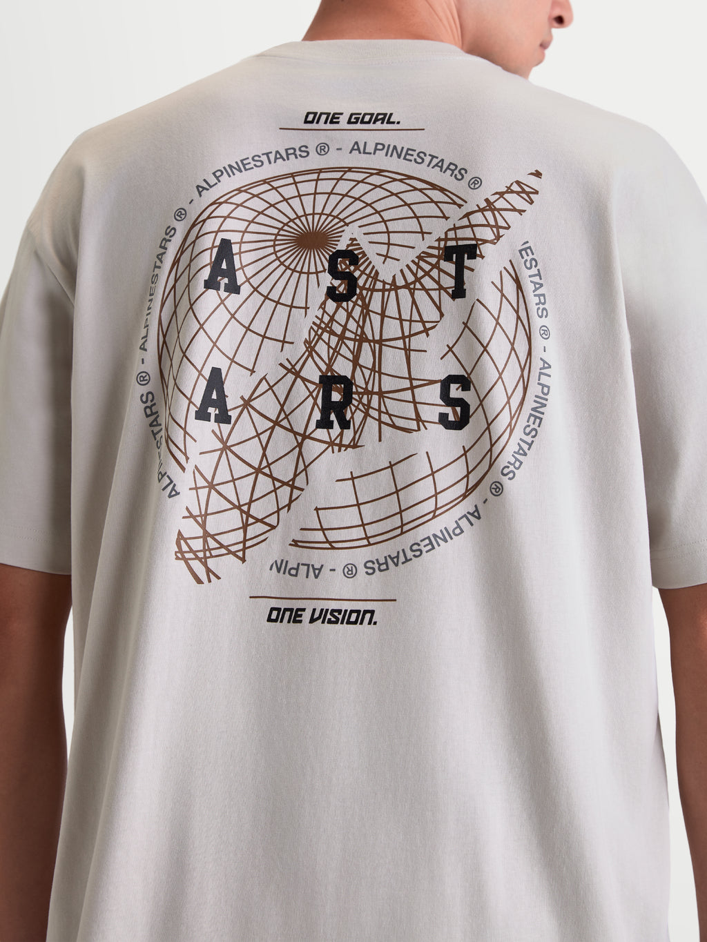 Alpinestars Latitude Oversized CSF T-Shirt, Kurzarm-T-Shirt, Zementgrau, Rückansicht am Model mit großer Globus-Grafik, ASTARS-Schriftzug und „One Goal One Vision“-Mottos, hochwertige Baumwoll-Polyester-Mischung, lässige Sportswear.