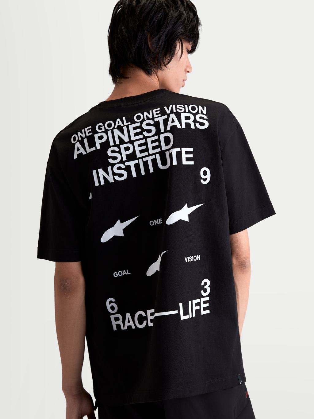 Alpinestars Institute Oversized CSF T-Shirt, Schwarz und Weiß, Sportswear T-Shirt in der Rückansicht am Modell mit Alpinestars Speed Institute und Race-Life Logo-Grafiken auf dem Rücken, entspannte Oversized-Passform, Baumwoll-Polyester-Mischung.
