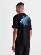Alpinestars Ghost Oversized CSF T-Shirt, Herren-Kurzarm-T-Shirt, Schwarz mit blauer Grafik. Rückansicht am Model zeigt ein großes Astars-Logo mit 'Racing Ahead' und 'One Goal. One Vision.' Text. Lockere Oversized-Passform in weicher Baumwoll-Polyester-Mischung für lässige Sportswear abseits der Rennstrecke.