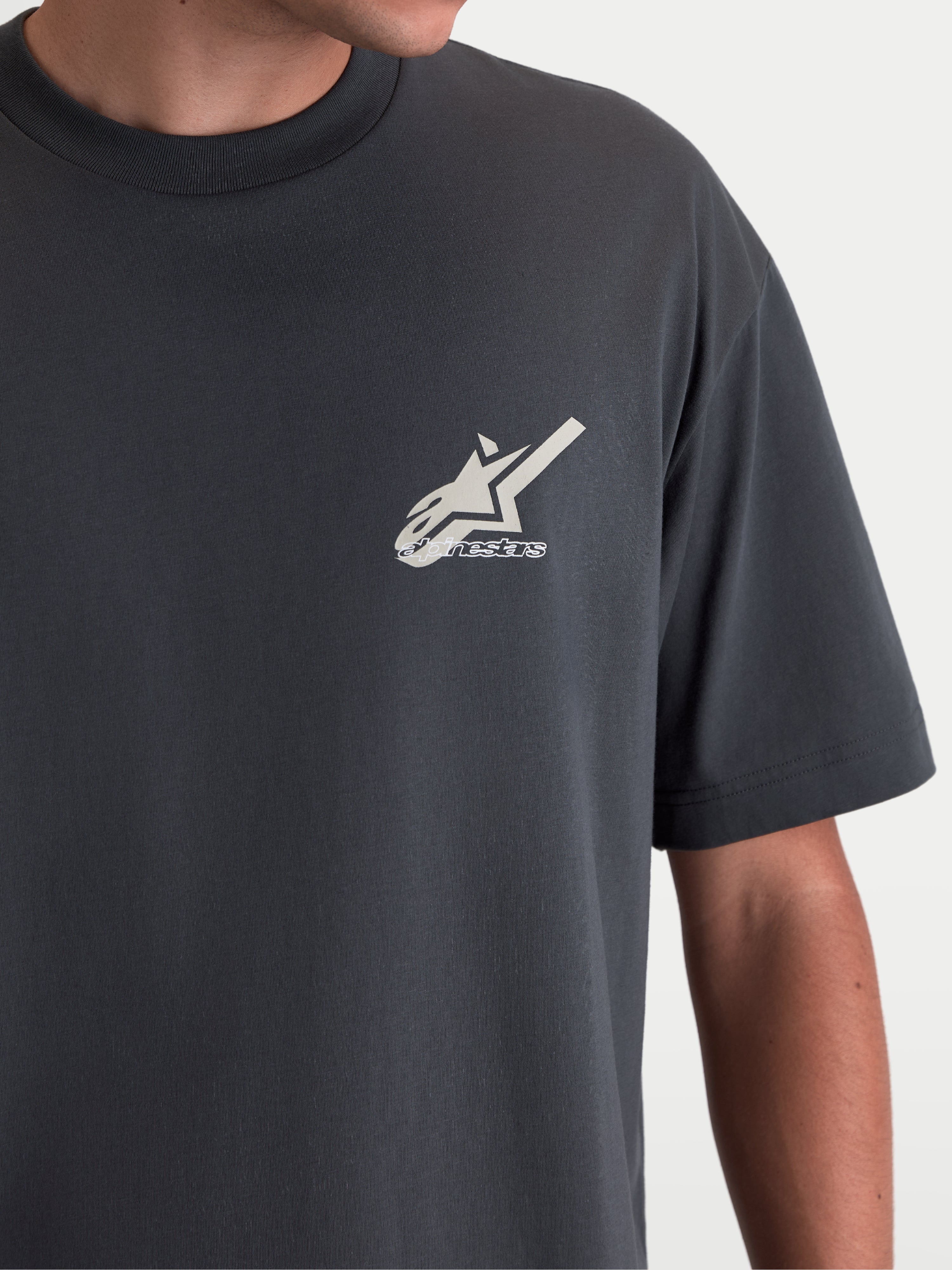 Alpinestars Ghost Oversized CSF T-Shirt, Kurzarm-Sportswear-T-Shirt, Anthrazit, Nahaufnahme der Astars-Logo-Grafik auf der Brust, Baumwoll-Polyester-Mischung mit lockerer Passform, Lifestyle-Detail am Model.
