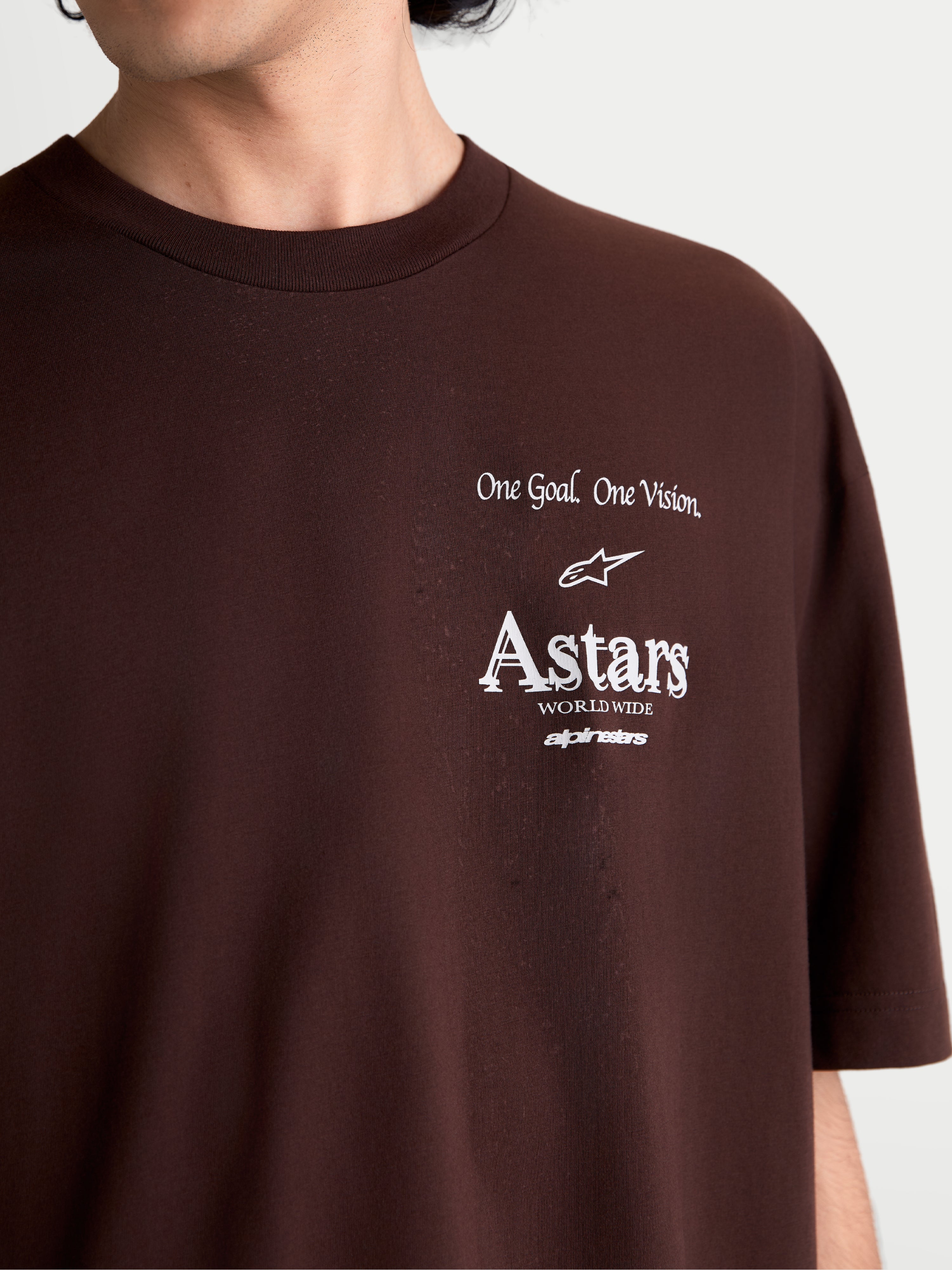 Alpinestars Post Oversized CSF T-Shirt, Kurzarm-Sportswear-T-Shirt, Braun, Nahaufnahme der weißen Brustgrafik mit „One Goal. One Vision.“ und Astars Worldwide Logo, weiches Baumwoll-Polyester-Mischgewebe.