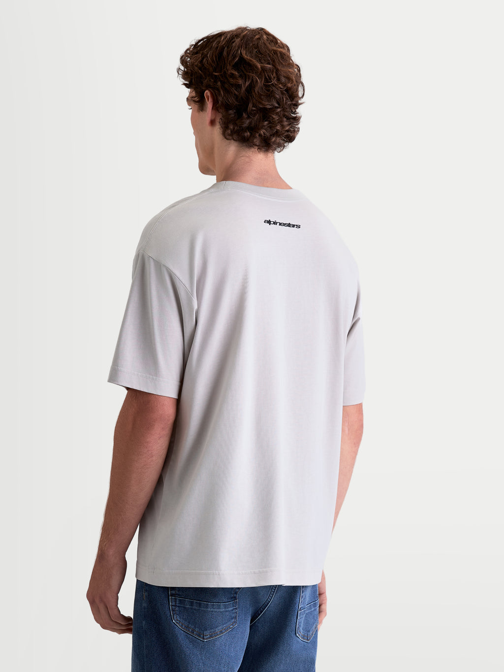 Alpinestars Prelude Oversized CSF T-Shirt, Kurzarm-Sportswear-T-Shirt, Grau mit schwarzem Alpinestars-Logo auf dem Rücken, lockere Passform, Baumwoll-Polyester-Mischgewebe, Rückansicht am Model.