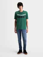 Alpinestars Singular CSF T-Shirt, lässiges Kurzarm-Sportswear-T-Shirt in Grün mit weißer gebogener Astars-Wortgrafik und schwarzem Brustdetail mit „One Goal. One Vision.“ Schriftzug, Frontansicht am Model, 60/40 Baumwoll-Polyester-Mischgewebe.
