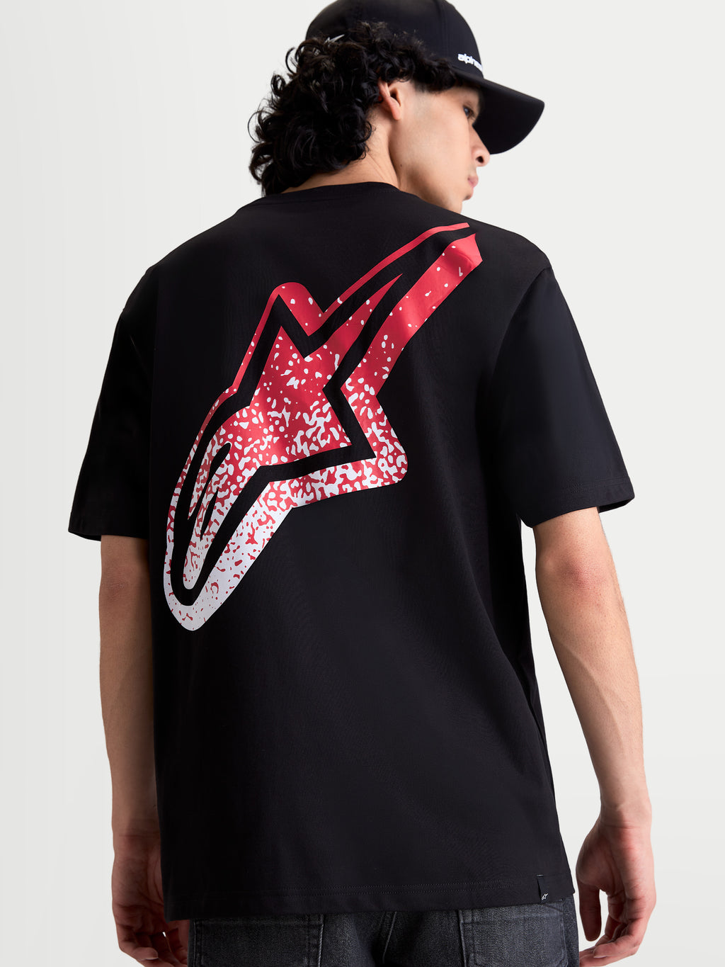 Alpinestars Meteor CSF T-Shirt, Kurzarm-Sportswear-T-Shirt in Schwarz, Rückansicht am Model mit großer rot-weißer Astars-Logo-Grafik im MX-Stil, lässige Motorsport-Bekleidung.