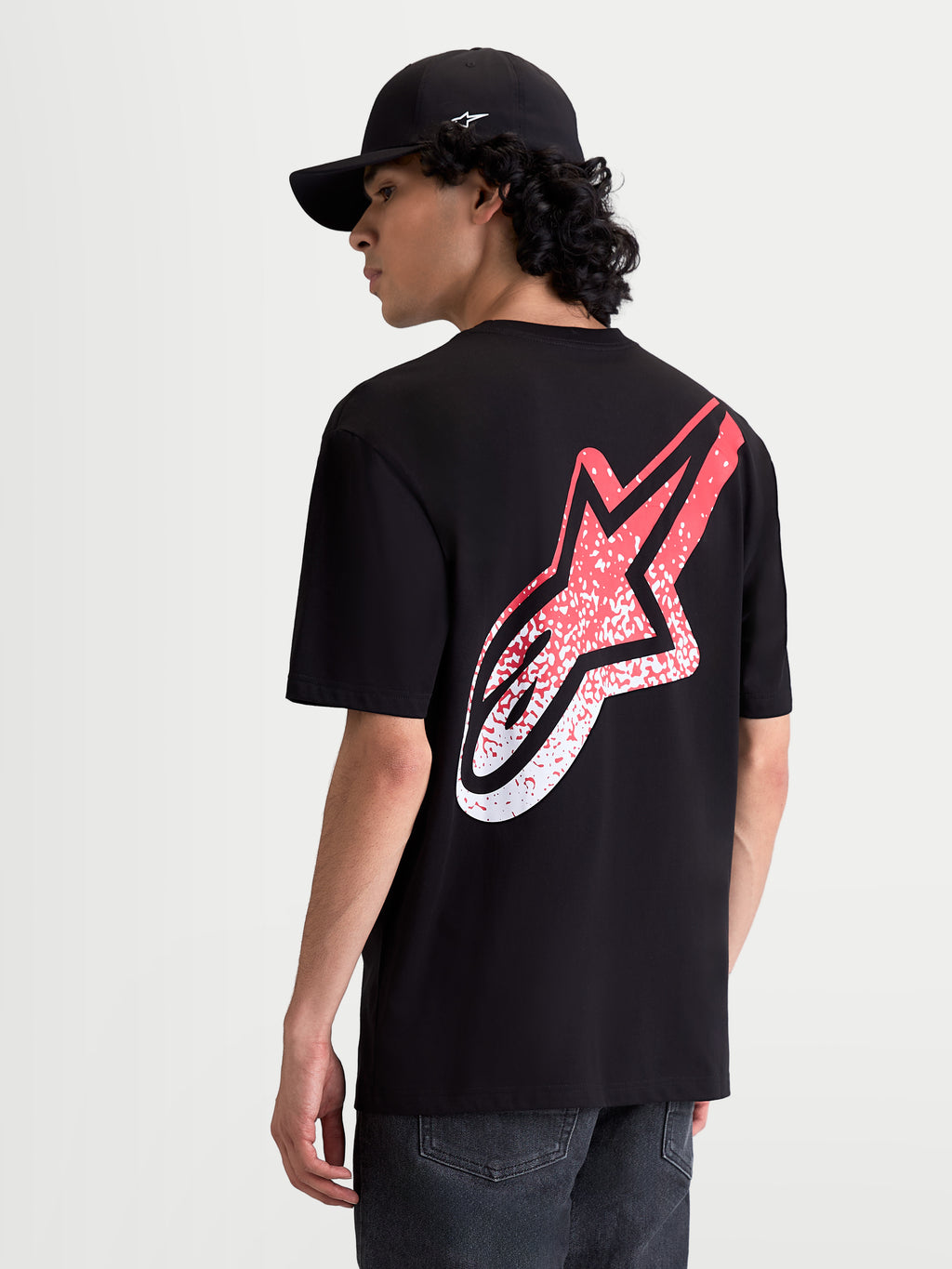 Alpinestars Meteor CSF T-Shirt, Kurzarm-Sportswear für Herren, Schwarz und Rot, mit einem großen MX-inspirierten Astars-Logo mit Farbverlauf auf dem Rücken, Rückansicht am Model, weiche Baumwoll-Polyester-Mischung für Alltagskomfort.