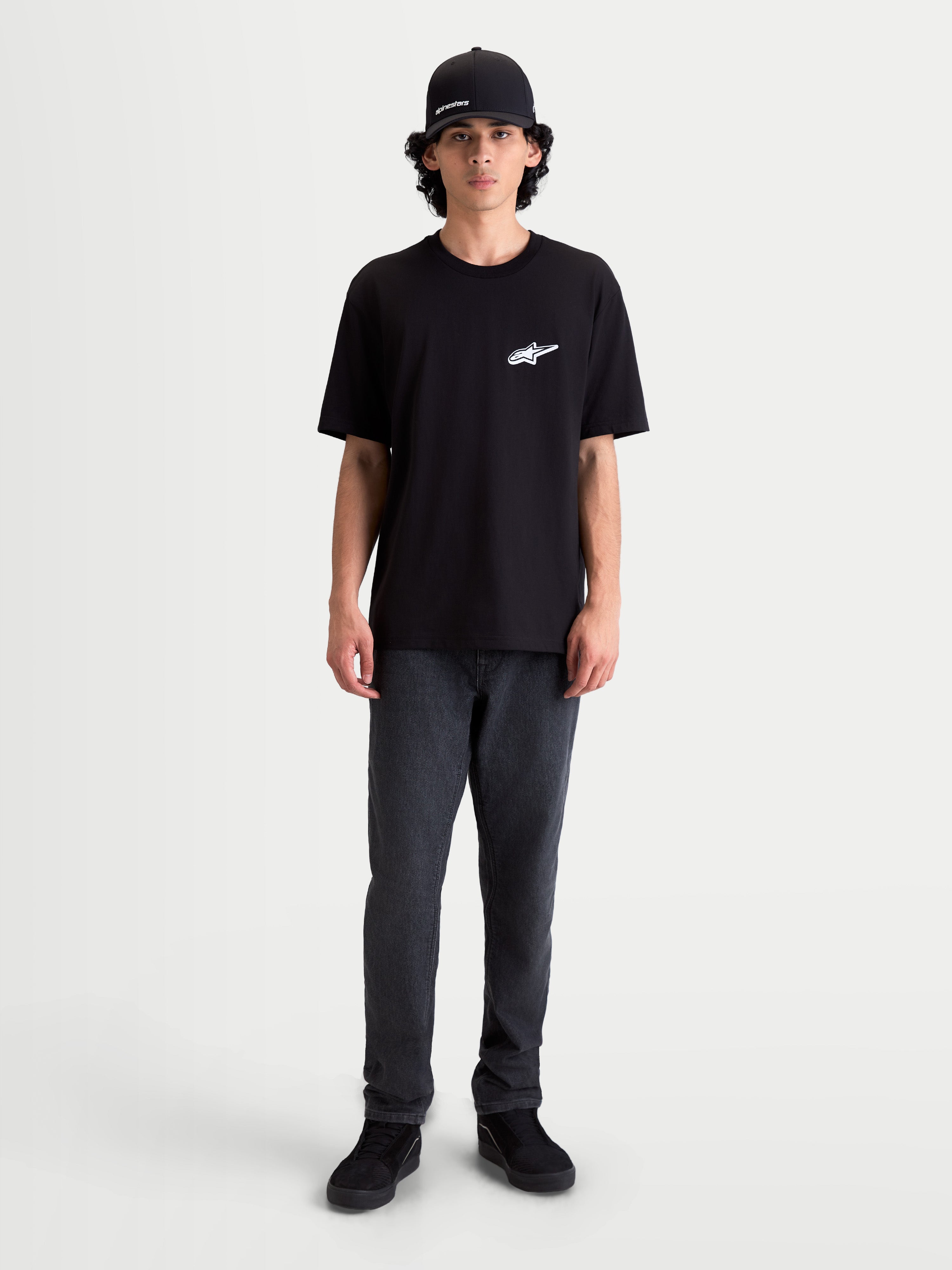 Alpinestars Meteor CSF T-Shirt, Kurzarm-Sportswear-T-Shirt, Schwarz mit weißem Astars-Logo auf der Brust, bequeme Baumwoll-Polyester-Mischung, lässiger Motorsport-Look am Model.