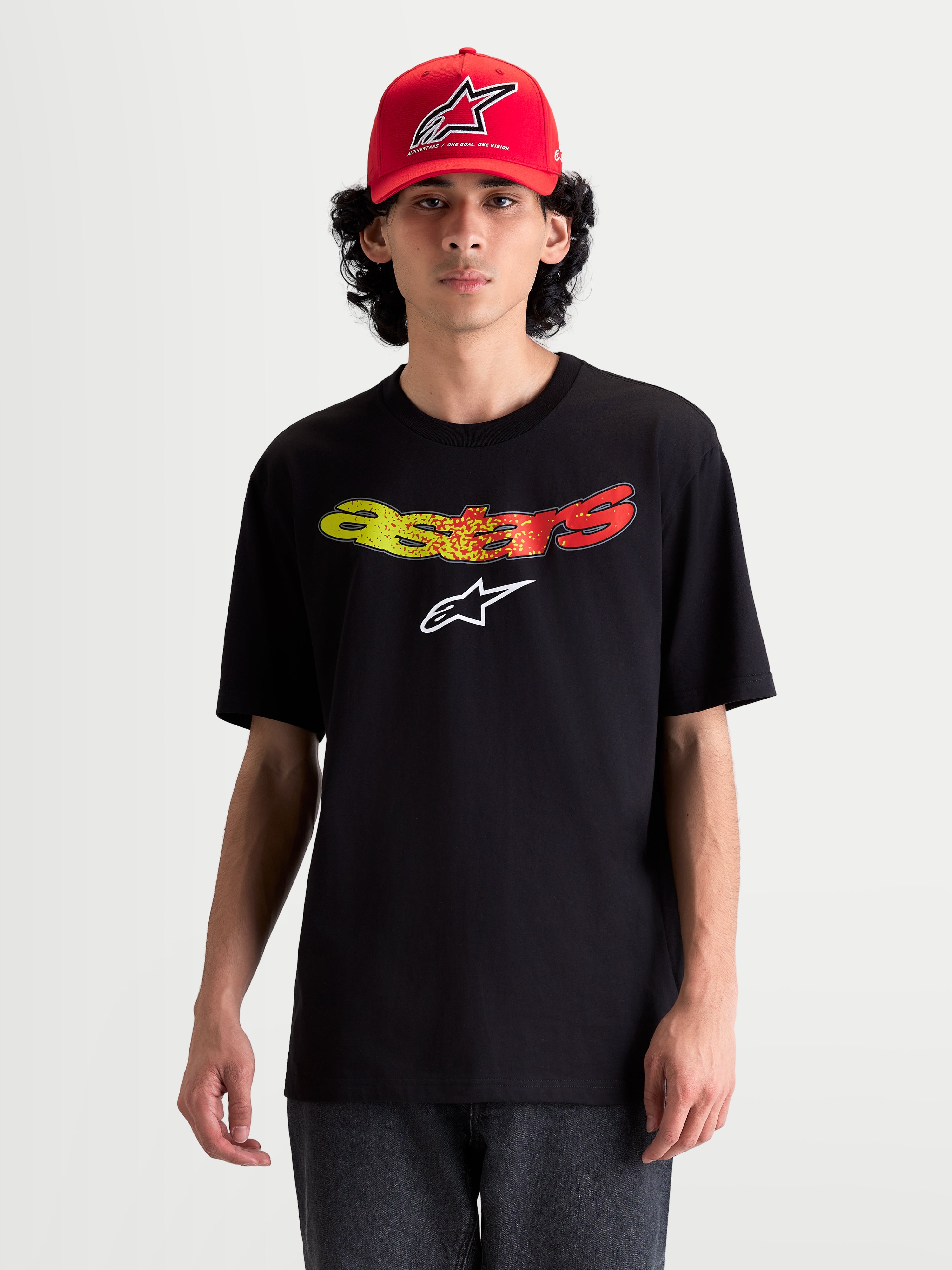 Alpinestars Elliptogrit CSF T-Shirt, Kurzarm-Sportswear-T-Shirt am Modell, Schwarz mit gebogenem Astars-Schriftzug in Rot- und Gelb-Farbverlaufsgrafik, weiche Baumwoll-Polyester-Mischung, lässige Alltagskleidung.