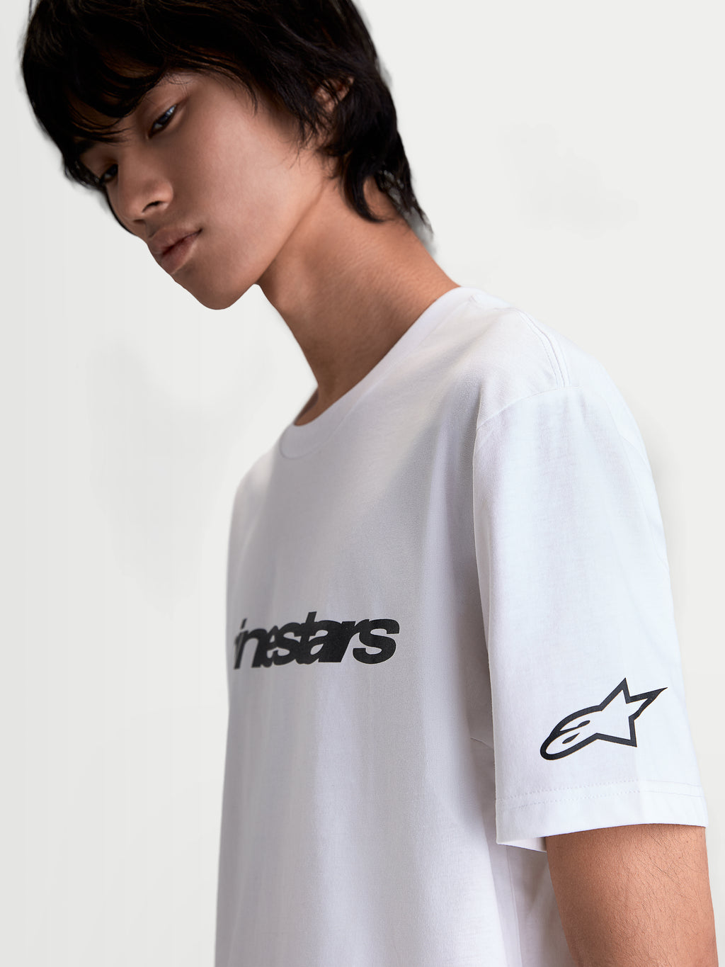 Alpinestars Race Wordmark CSF T-Shirt, lässiges Kurzarm-Sportswear-T-Shirt in Weiß und Schwarz, mit markantem Alpinestars-Schriftzug auf der Vorderseite und Ageless-Stern-Logo am Ärmel, weicher Grafikdruck, Baumwoll-Polyester-Mischgewebe, Seitenansicht am Modell.