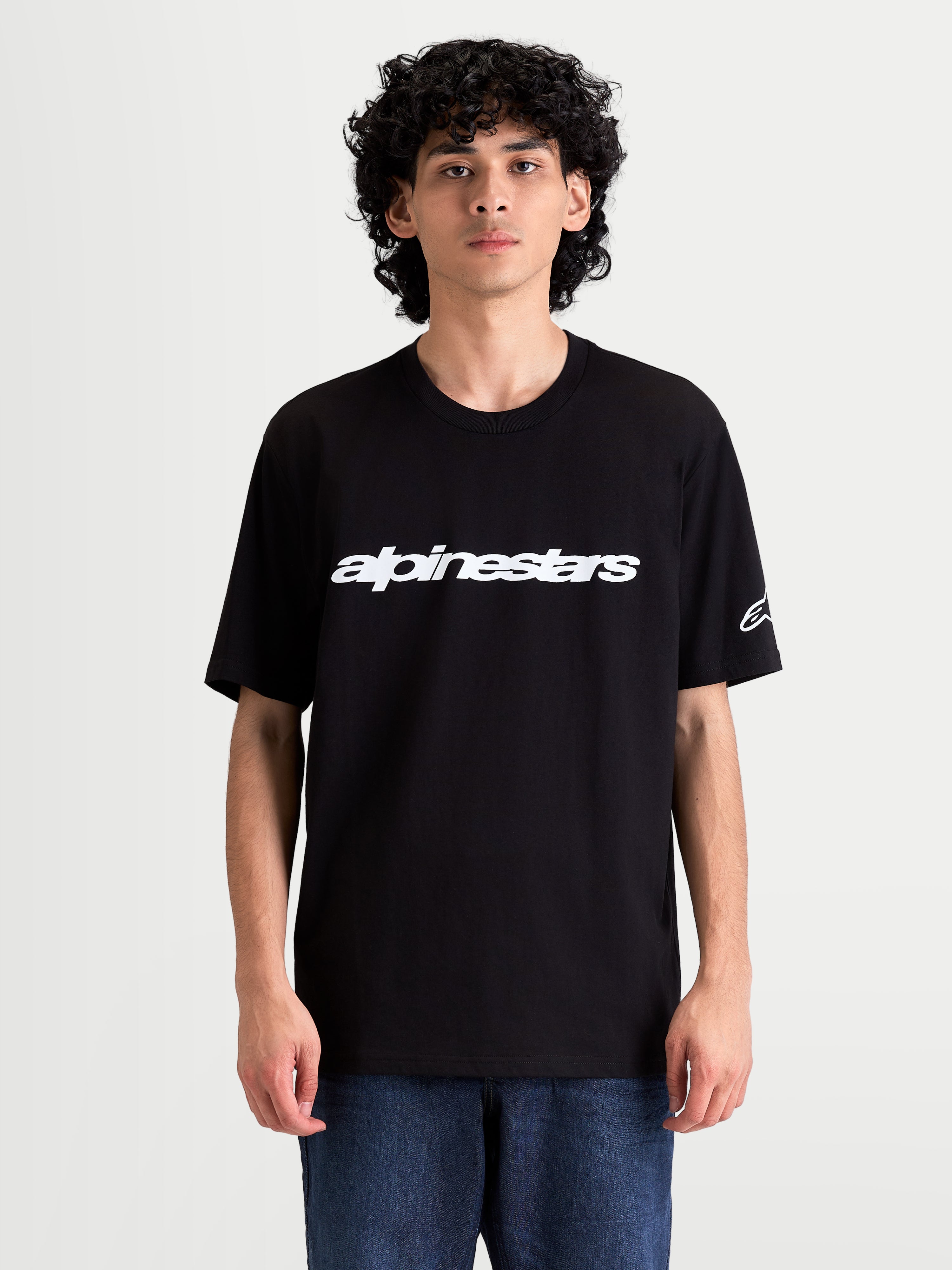 Alpinestars Race Wordmark CSF T-Shirt, Kurzarm-Sportswear für Herren am Model, Schwarz und Weiß, mit markantem Alpinestars-Schriftzug auf der Brust und Ageless-Logo am Ärmel.
