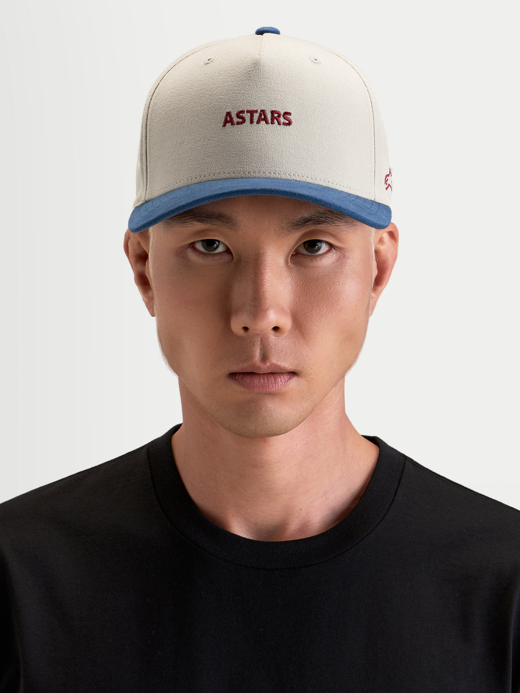 Alpinestars County Canvas Kappe, lässige Sportswear-Mütze in Sandfarben und Blau an einem Model, mit strukturierter Krone, gebogenem Schirm und gesticktem Astars-Logo auf der Vorderseite