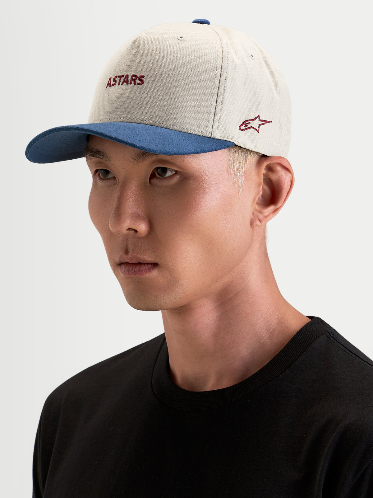 County Canvas Kappe, sandfarbene und blaue Sportswear-Kappe mit gebogenem Schirm und gesticktem Astars-Logo, getragen von einem Model