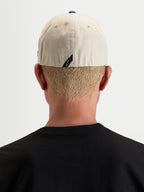 Alpinestars County Canvas Kappe, lässige Sportswear-Kappe in Sand und Blau, Rückansicht an einem Model mit Flex-Rückseite und dezentem Rückenlabel-Branding aus Oxford-Baumwollgewebe