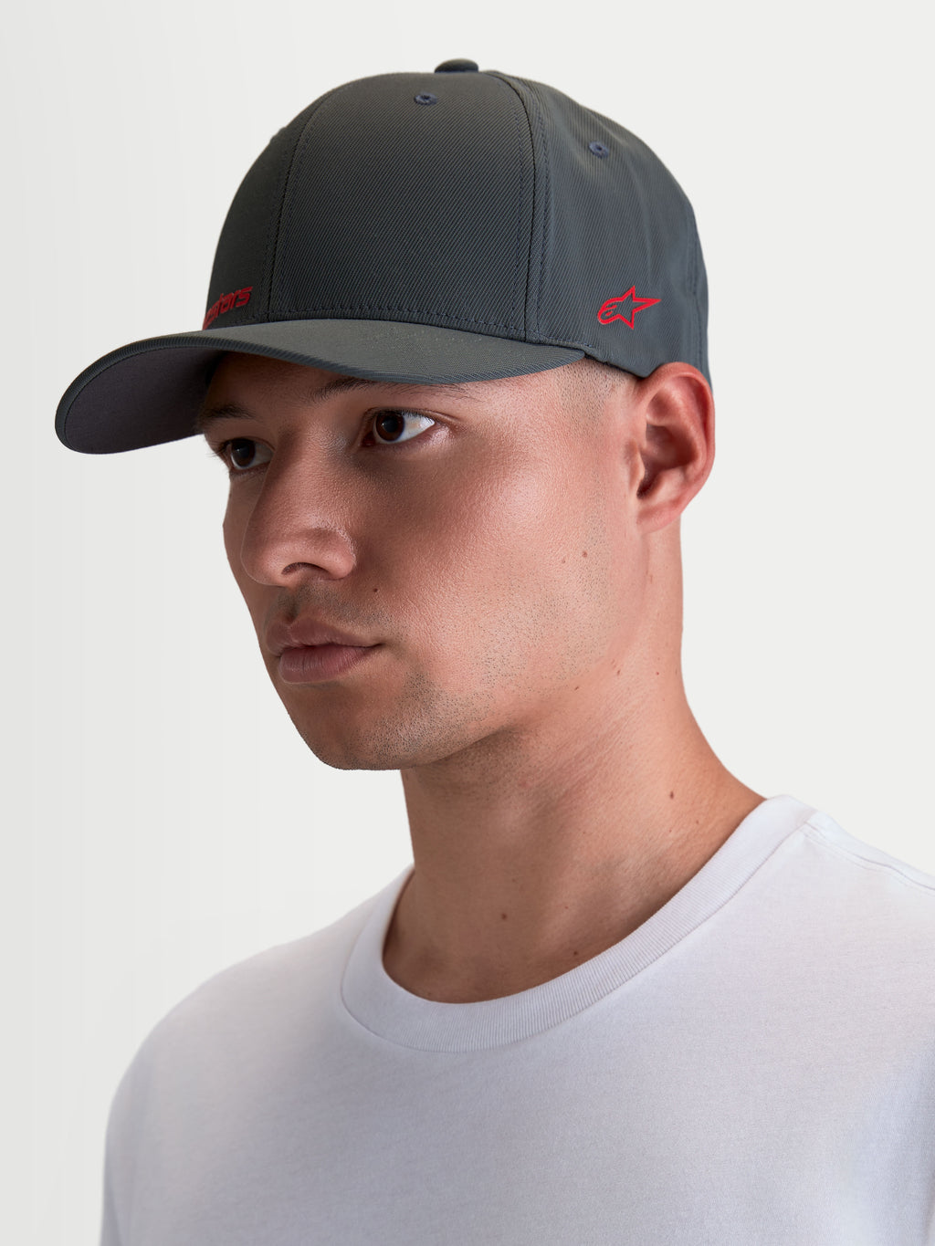Alpinestars Points Kappe, Sportswear-Kappe mit gebogenem Schirm am Modell getragen, Dunkelgrau mit rotem Astars-Logo, leichtes Nylon-Tactel, Flex-Back-Passform für Alltagskomfort.