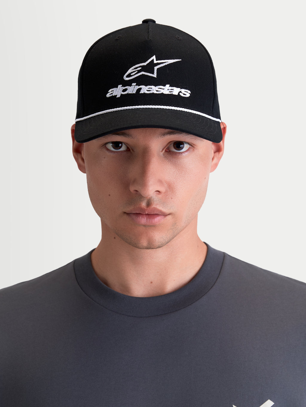 Alpinestars Combo Logo Snapback-Kappe, Motorrad-Sportswear-Kappe, Unisex, Schwarz und Weiß, mit gebogenem Schirm, strukturierter Krone und besticktem Astars-Logo, 100 % Baumwolltwill, Frontansicht am Model.