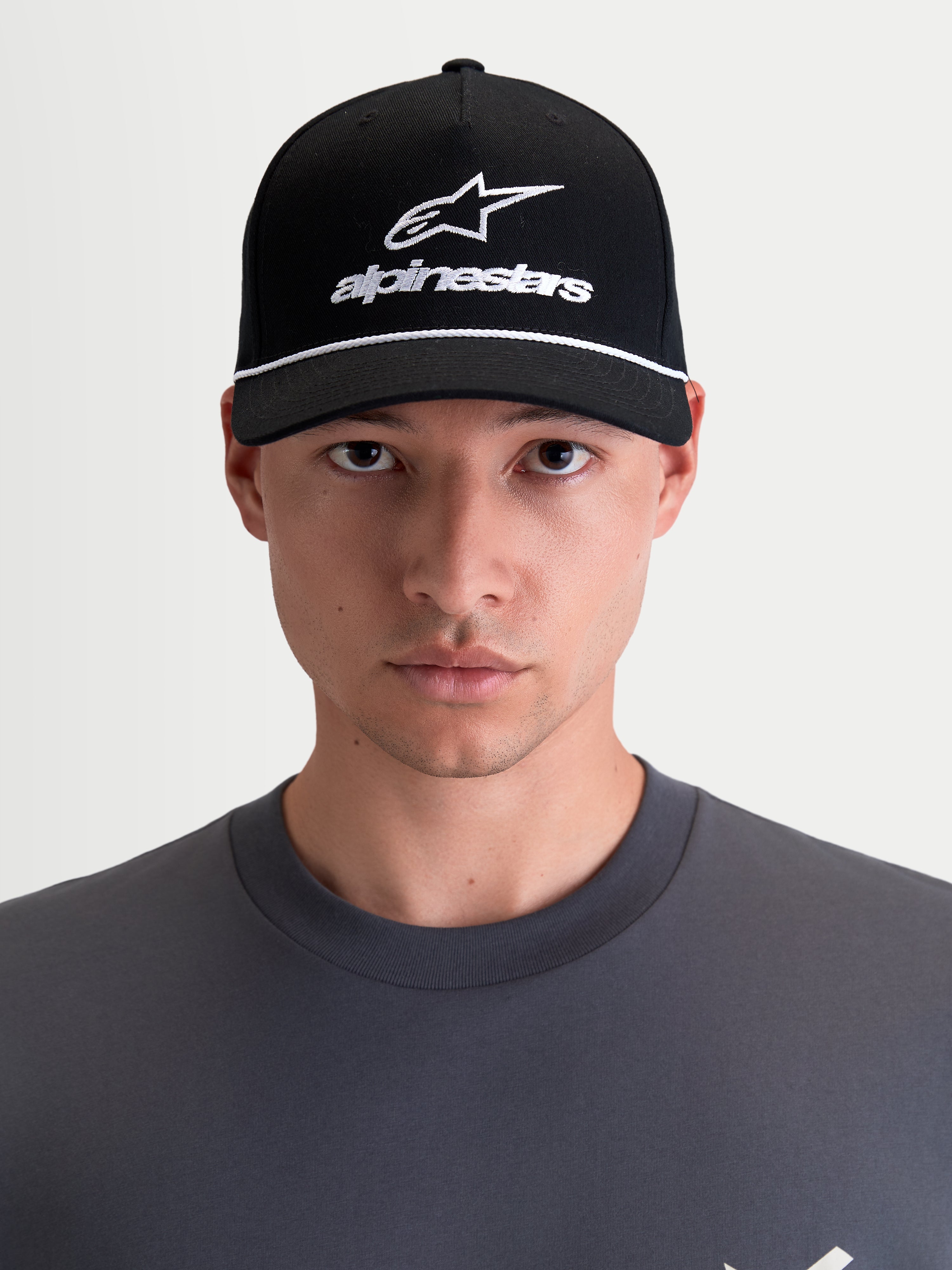 Alpinestars Combo Logo Snapback-Kappe, Motorrad-Sportswear-Kappe, Unisex, Schwarz und Weiß, mit gebogenem Schirm, strukturierter Krone und besticktem Astars-Logo, 100 % Baumwolltwill, Frontansicht am Model.