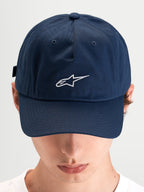 Alpinestars Dylan Dad-Kappe, blaue Baumwolltwill-Sportswear-Kappe mit gebogenem Schirm und weißer Astars-Logo-Stickerei auf der Vorderseite, getragen von einem Model