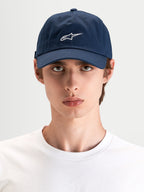 Alpinestars Dylan Dad-Kappe, marineblaue Sportswear-Kappe mit weißer Astars-Logo-Stickerei, gebogenem Schirm und unstrukturierter niedriger Krone, getragen von einem Model