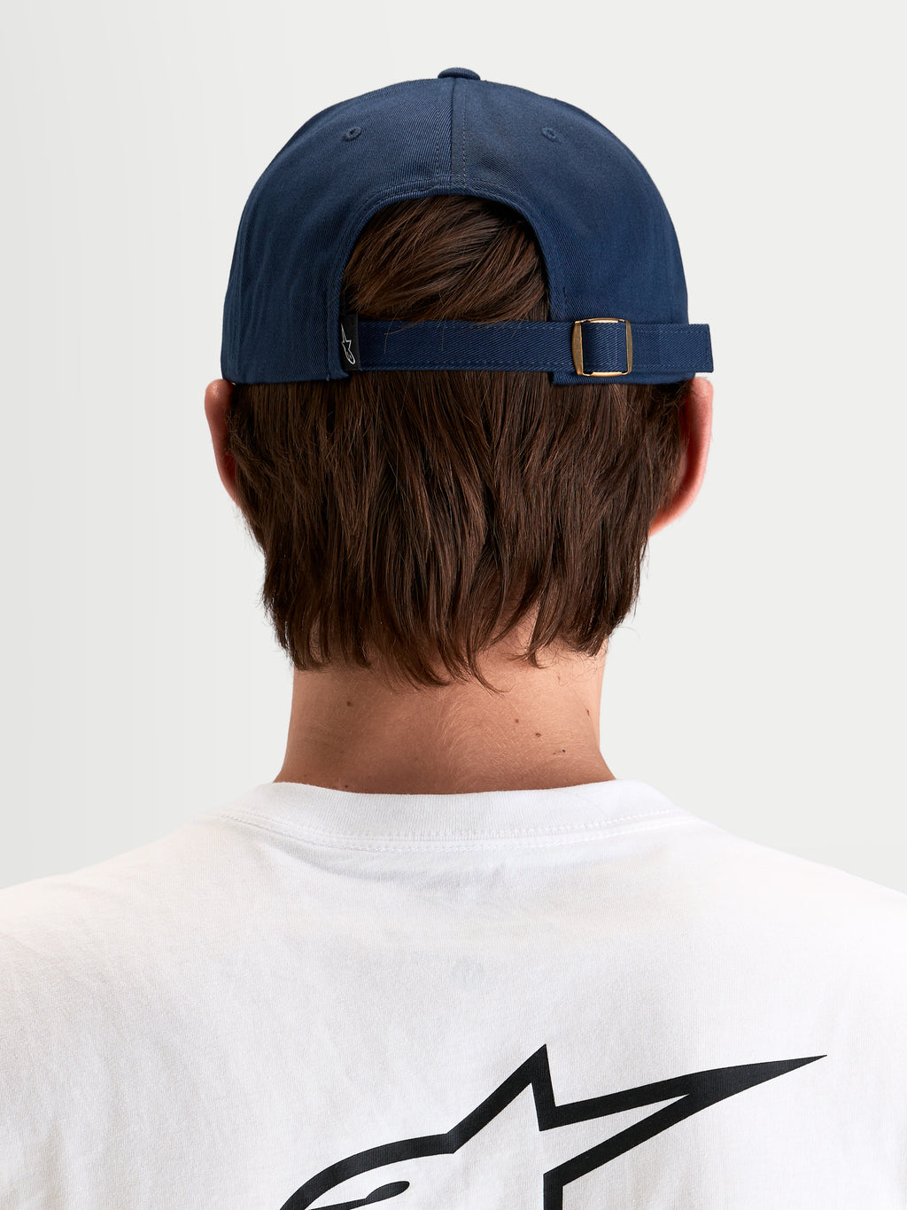 Alpinestars Dylan Dad-Kappe, lässige Sportswear-Kappe in Marineblau, Rückansicht des verstellbaren Riemenverschlusses mit Metallschnalle und kleinem Astars-Logoetikett, getragen von einem Model
