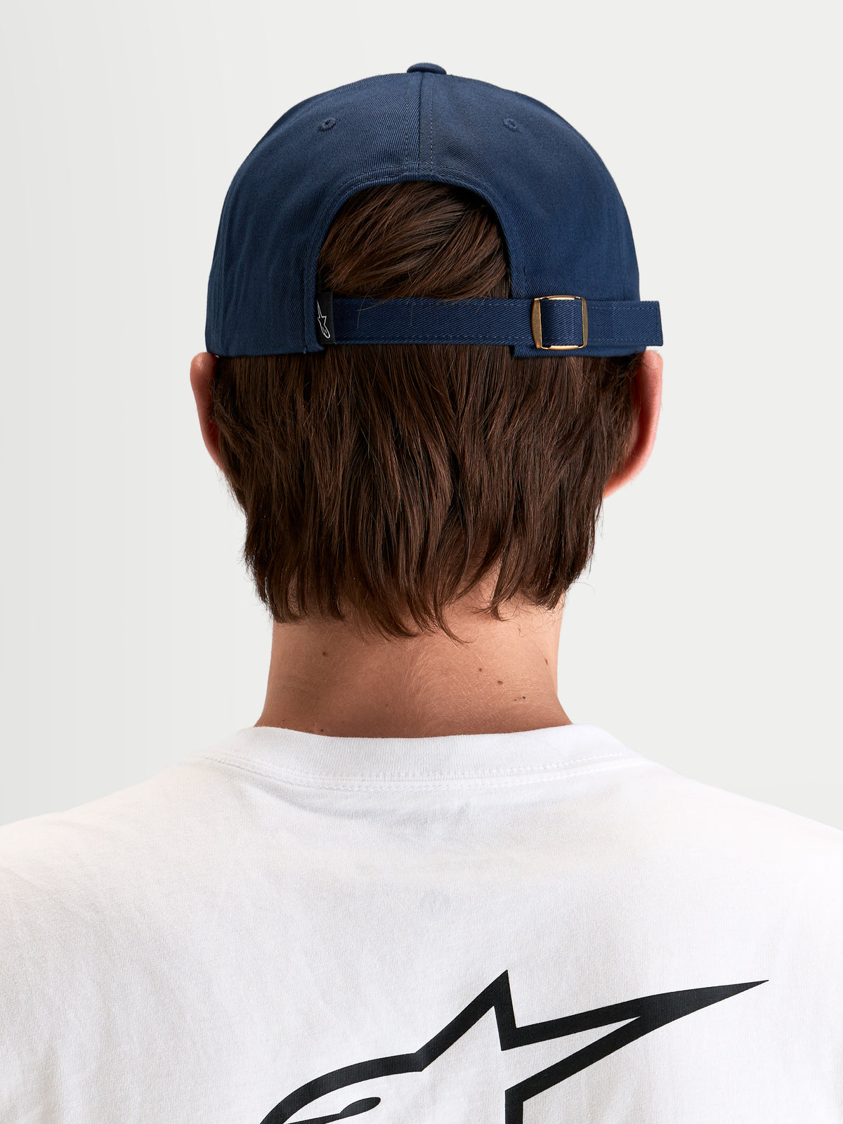 Alpinestars Dylan Dad-Kappe, lässige Sportswear-Kappe in Marineblau, Rückansicht des verstellbaren Riemenverschlusses mit Metallschnalle und kleinem Astars-Logoetikett, getragen von einem Model
