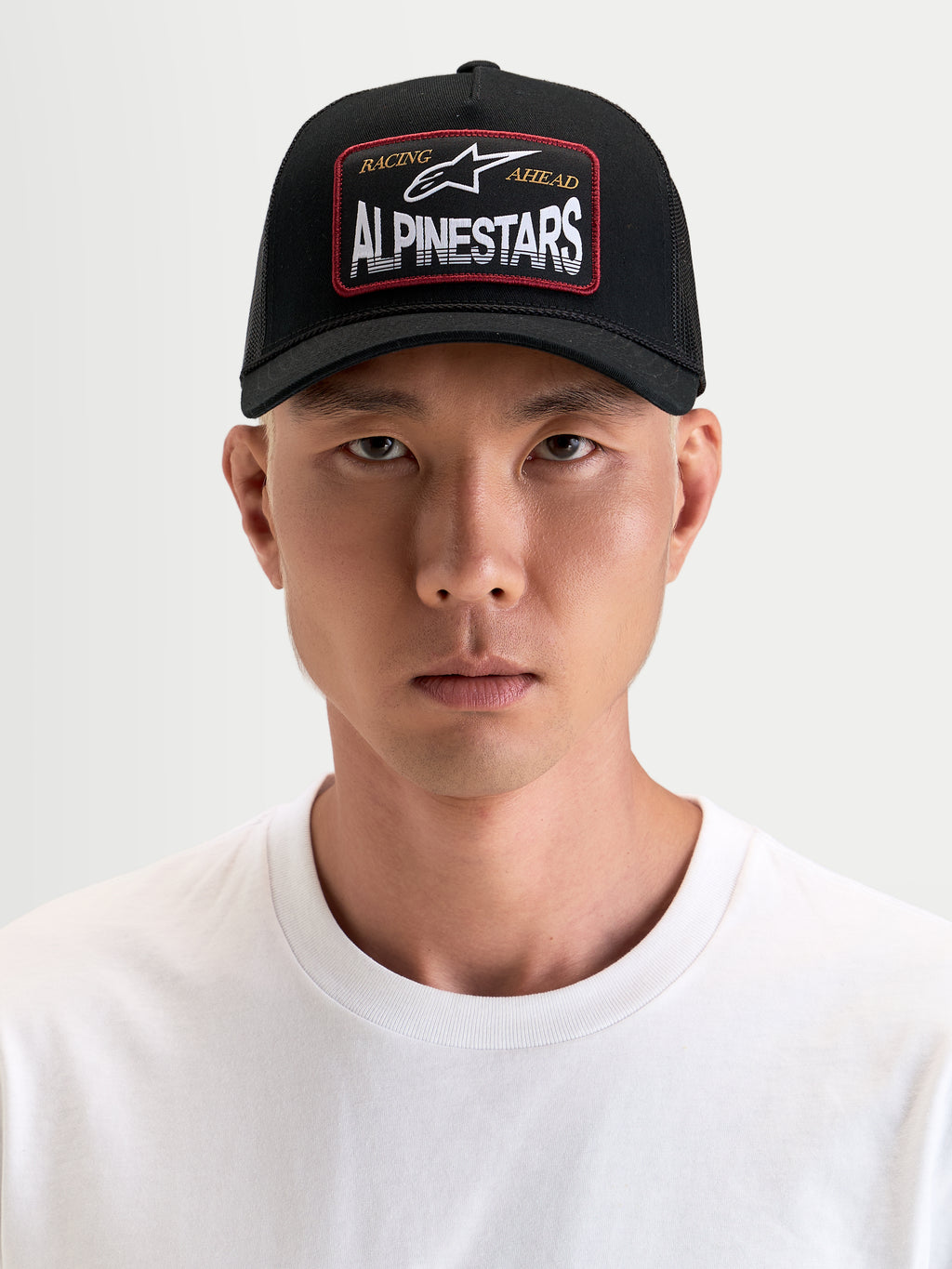 Alpinestars Hemmings Trucker-Kappe, schwarze Sportswear-Kappe mit gebogenem Schirm und atmungsaktiver Mesh-Rückseite, mit gewebtem Alpinestars Logo-Patch auf der Vorderseite, getragen von einem Model