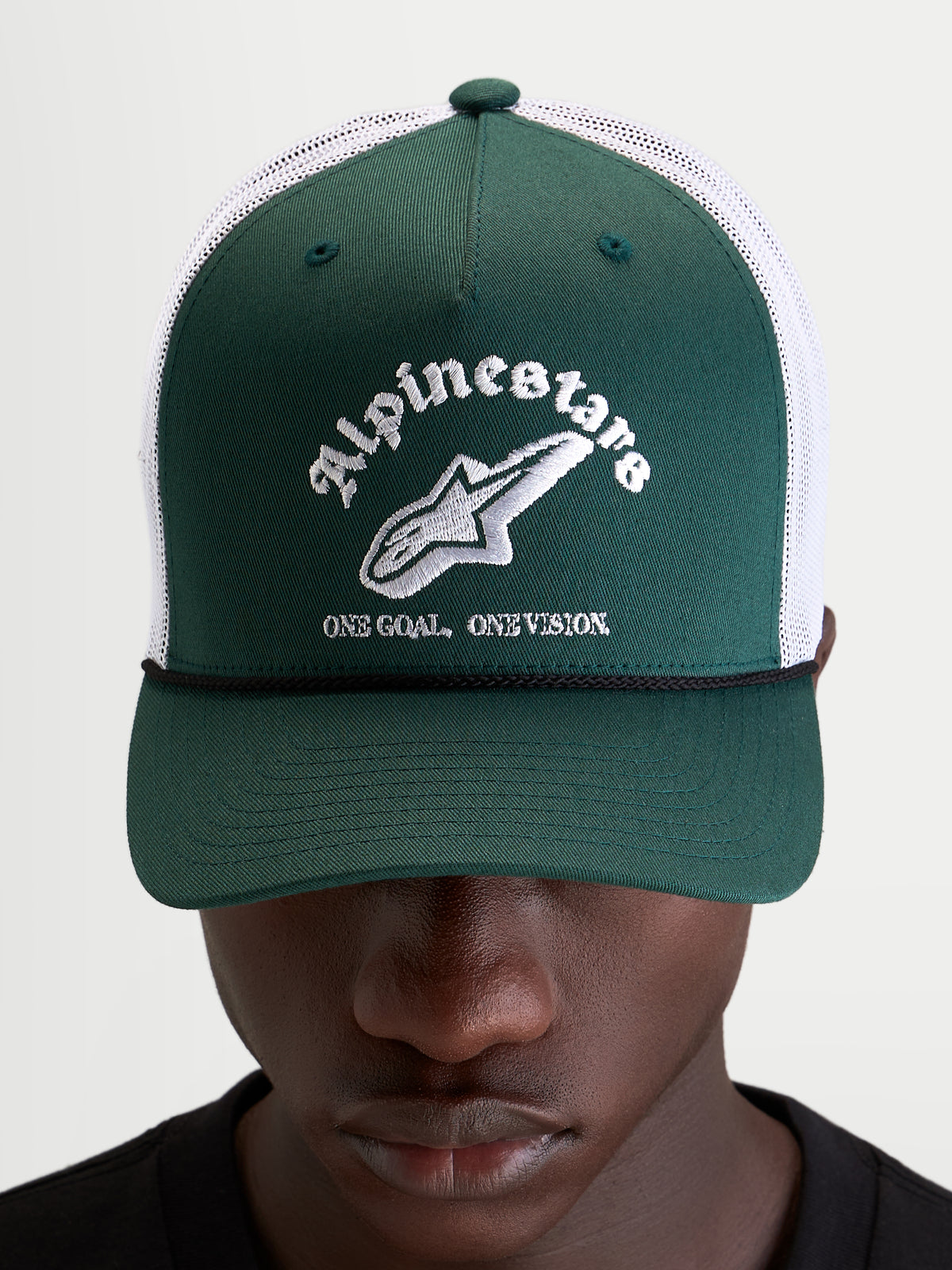 Alpinestars Baron Trucker-Kappe, grüne und weiße Trucker-Mütze mit gebogenem Schirm, strukturierter Twill-Front und gesticktem Logo auf der Vorderseite, getragen von einem Model