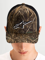 Alpinestars Thicket Realtree Trucker-Kappe, Sportswear Trucker-Mütze in Realtree-Camo und Schwarz, getragen von einem Model, mit gebogenem Schirm, strukturierter Krone und weißem, gesticktem Astars-Logo auf der Front