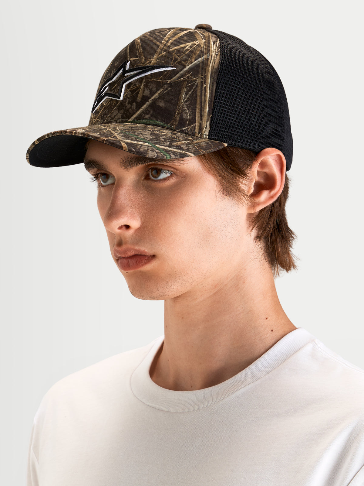 Alpinestars Thicket Realtree Trucker-Kappe, Sportswear Trucker-Mütze in Realtree-Camo und Schwarz, gebogener Schirm, strukturierte Krone und 3D-besticktes Astars-Logo, getragen von einem Model