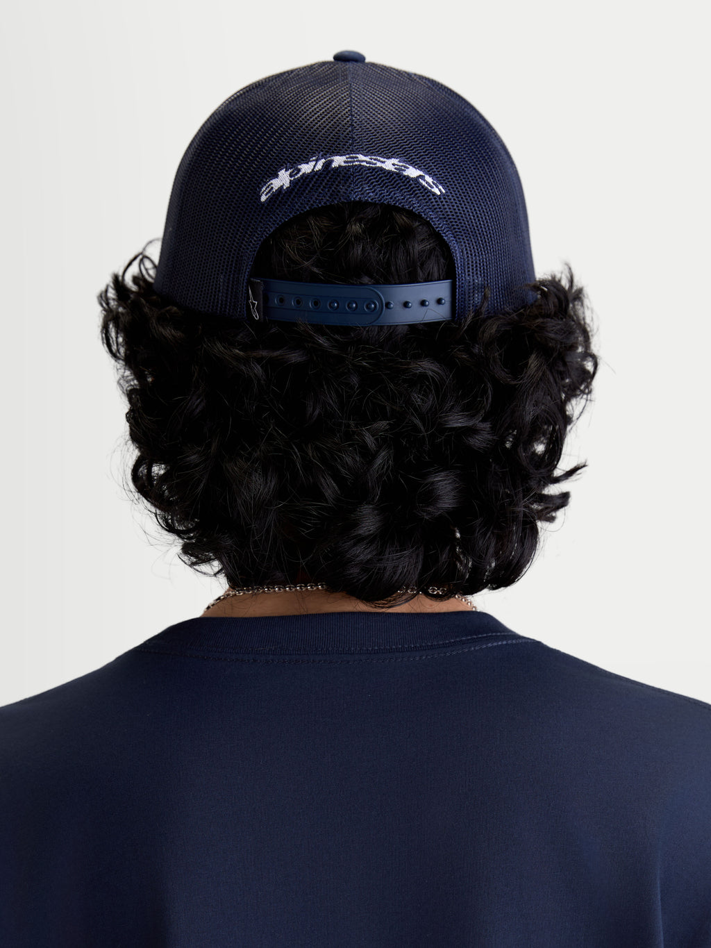 Alpinestars Meteorite Trucker-Kappe, Sportswear-Kopfbedeckung, Rückansicht am Modell, Blau, mit Poly-Mesh-Rückseite, verstellbarem Snapback-Verschluss und weißer Alpinestars-Logo-Stickerei.