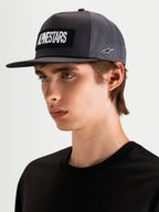 Alpinestars Ten Trucker Hat, flat bill sportswear cap in dark grey, worn by a model, featuring a front embroidered Alpinestars word logo patch and side Astars logo embroidery.