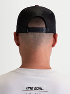 Alpinestars Hotlink Trucker-Kappe, Motorsport-Lifestyle-Cap, Unisex, Braun und Schwarz, Rückansicht am Modell mit verstellbarem Snapback-Verschluss, Mesh-Einsätzen für Atmungsaktivität und Premium-Branding-Detail.