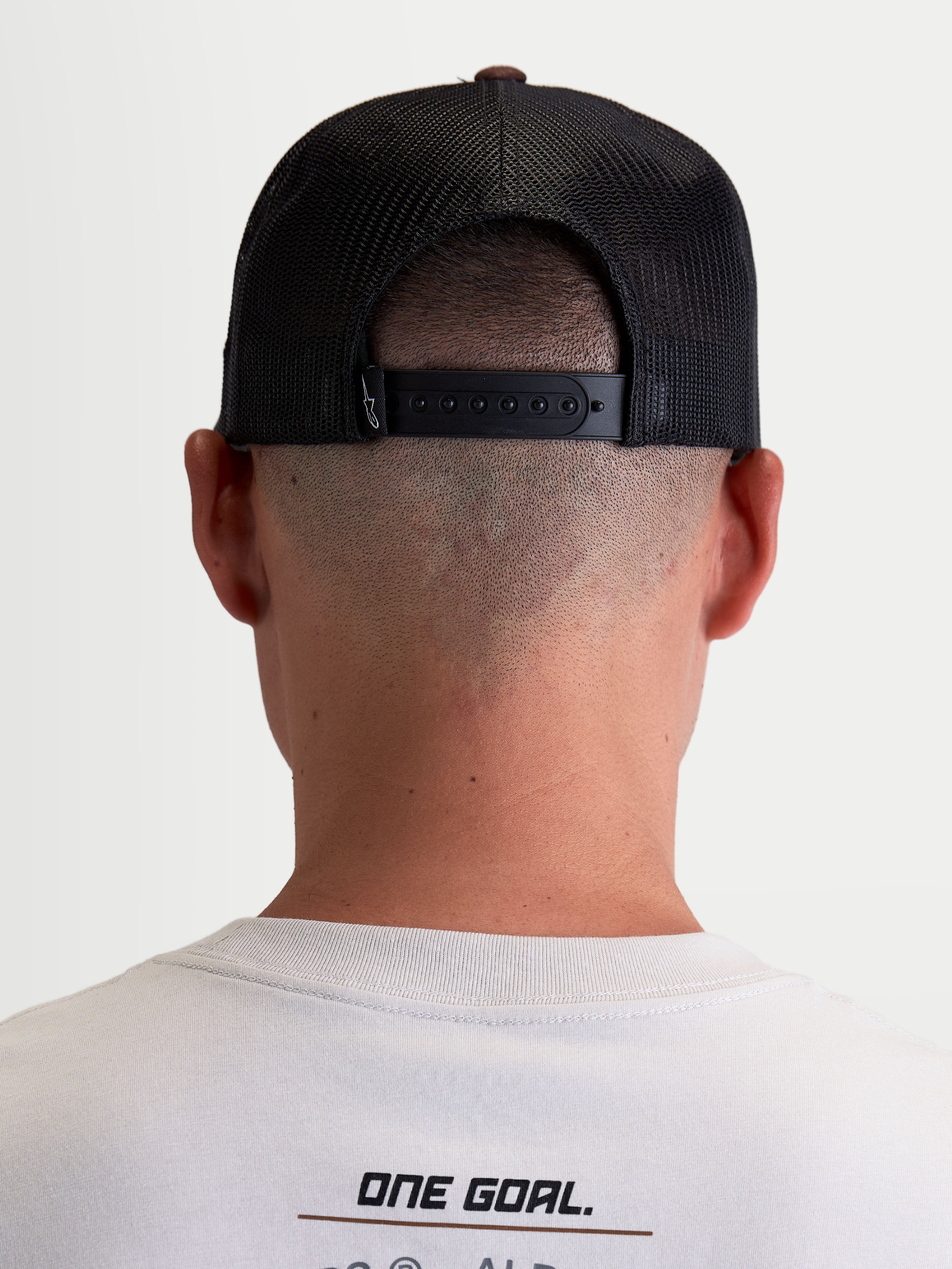 Alpinestars Hotlink Trucker-Kappe, Motorsport-Lifestyle-Cap, Unisex, Braun und Schwarz, Rückansicht am Modell mit verstellbarem Snapback-Verschluss, Mesh-Einsätzen für Atmungsaktivität und Premium-Branding-Detail.