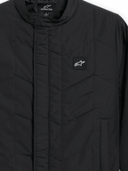 Alpinestars Precedent Jacke, gesteppte Sportswear-Jacke, Schwarz, Nahaufnahme mit ikonischem schrägem Steppmuster, niedrigem Stehkragen, verdecktem Frontreißverschluss und kleinem Logo-Patch auf der Brust