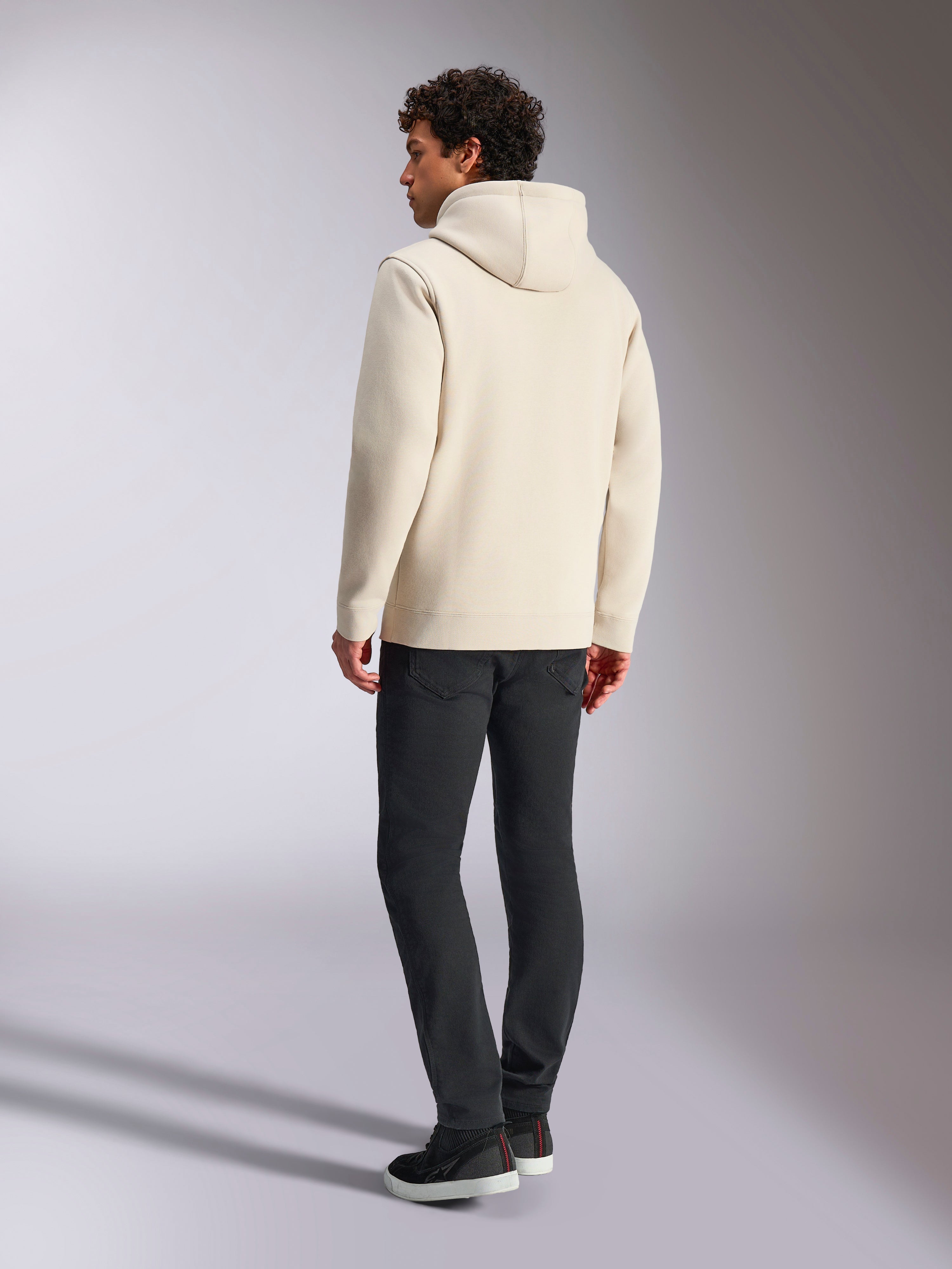 Alpinestars Always V3 Hoodie, Off-White, Rückansicht eines männlichen Models mit Hoodie und schwarzer Hose, lässige vom Motorsport inspirierte Streetwear, minimalistisches Design mit Kapuze und geripptem Saum