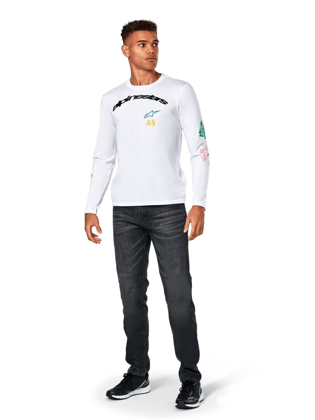 Alpinestars Brundo CSF Langarmshirt, Weiß, lässige Sportbekleidung, mit schwarzem 'alpinestars' Brust-Schriftzug, blauem Stern-Logo und gelben 'AS' Initialen, bunte Grafiken am Ärmel, kombiniert mit dunkler Jeans und schwarzen Sneakern