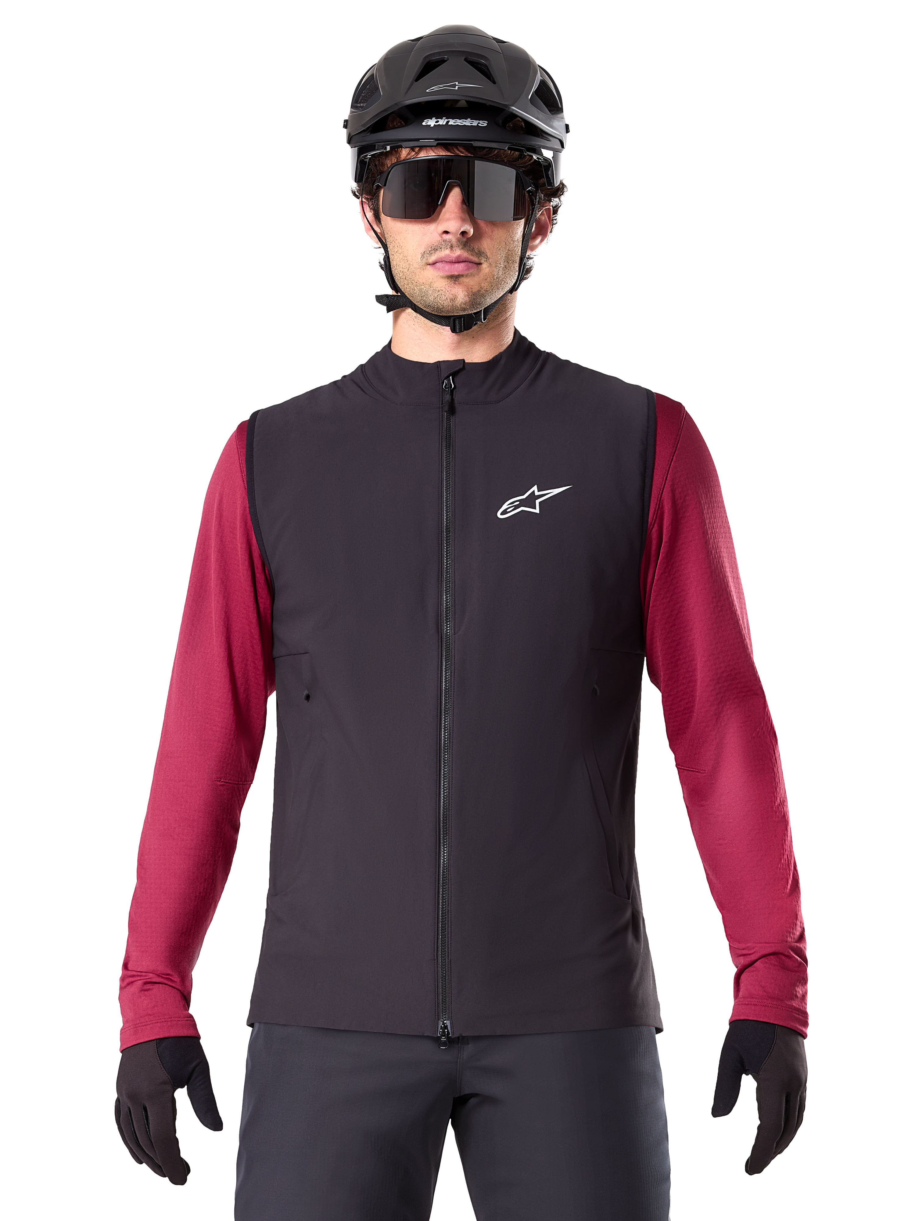 Alpinestars A-Dura Thermoweste, schwarze isolierte Radweste, getragen von einem Modell mit weinrotem Langarmtrikot, schwarzem MTB-Helm und Sonnenbrille, mit weißem Logo auf der Brust, leichter Wärmeschutz fürs Mountainbiken