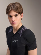 Alpinestars A-Motion Plasma Protection Jacket - Short Sleeve, Black Camo, close-up of a male model wearing the protective gear, featuring padded chest and shoulder panels with grey camouflage accents and a white Alpinestars logo.