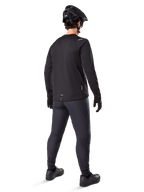 Alpinestars A-Dura Thermo-Hose, Mountainbike-Hose, Schwarz, Rückansicht mit passendem Langarm-Trikot, schwarzem MTB-Helm und Handschuhen, technische Fahrradausrüstung für kaltes Wetter