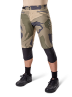 Alpinestars A-Dura Camo Liner Shorts, Mountainbike-Shorts, braunes Camo-Muster, Vorderansicht mit Reißverschlusstaschen und seitlichen Taillenverstellern, getragen mit schwarzen Knieschonern und schwarzen Fahrradschuhen, strapazierfähige MTB-Ausrüstung