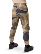 Alpinestars A-Dura Camo Hose, MTB-Hose, braunes Camouflage-Muster mit beigen und dunkelgrauen Akzenten, Rückansicht mit schwarzen Sneakern, schmal zulaufende Beine und elastische Bündchen, strapazierfähiger 2-Wege-Stretchstoff für Mountainbiking